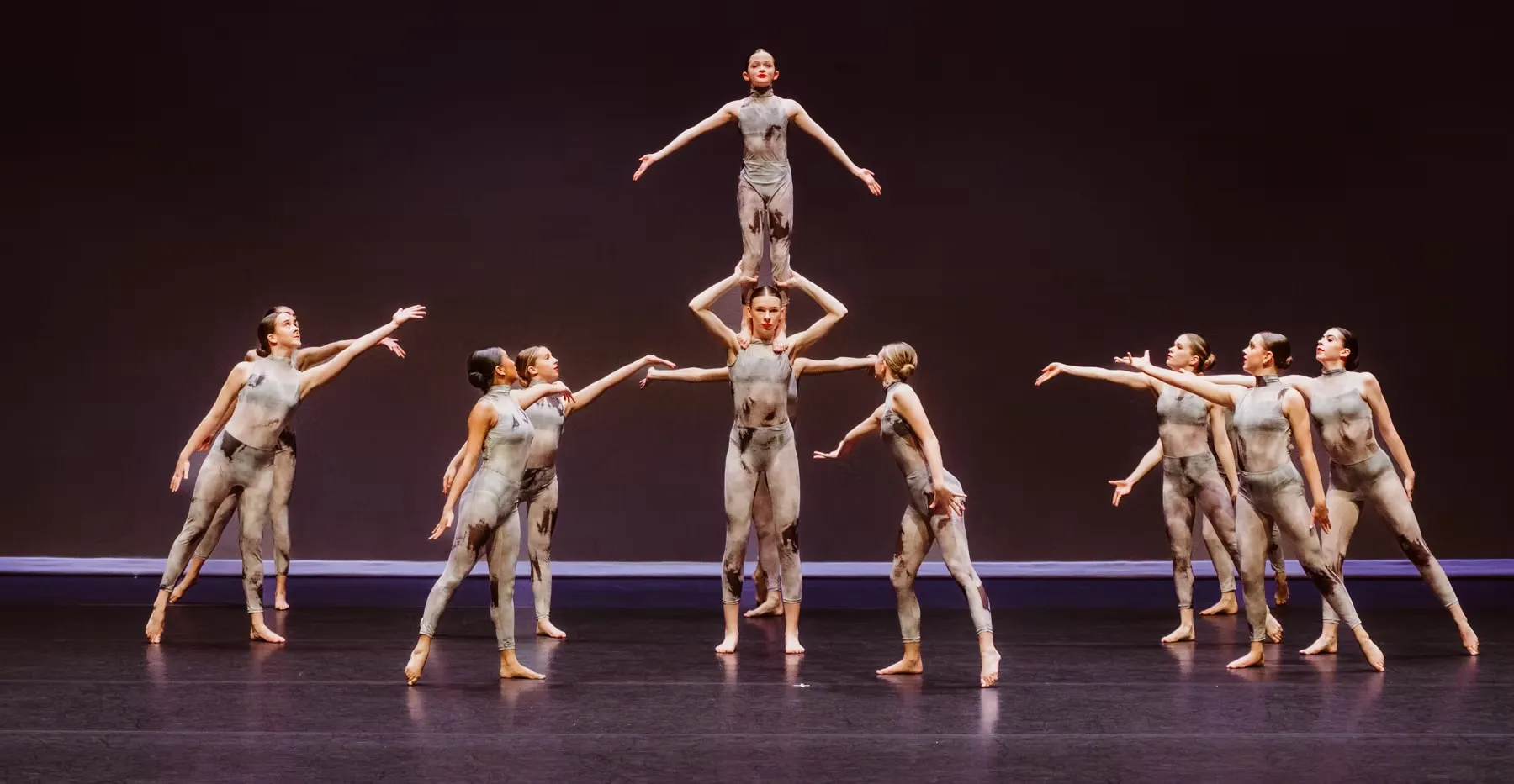 Dancers in a pyramid formation on stage, performing at the Vernon Performing Arts Festival.